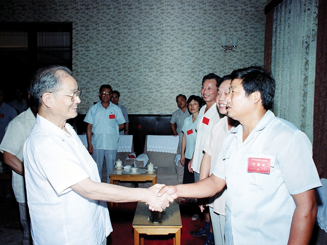1990年8月7日，中共中央政治局常委、中组部部长宋平（左一）在莱西召开的全国村级政权建设会议上与九间棚村党支部书记刘嘉坤握手